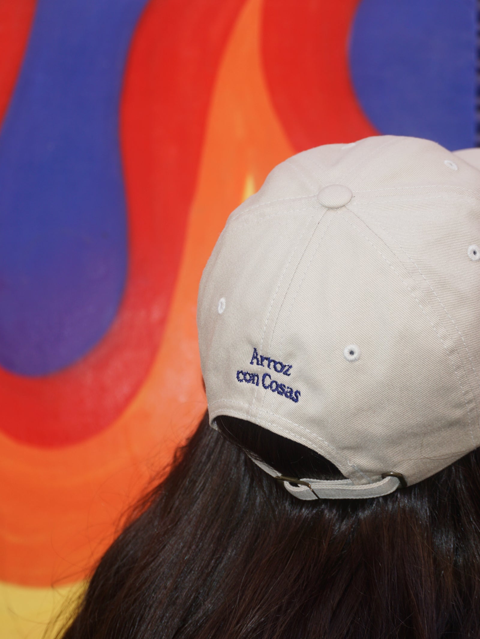 Person wearing a beige cap with text against a colorful abstract background